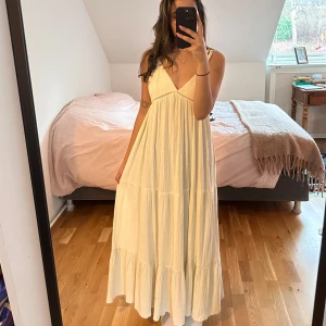 Vit långklänning med knytband - Säljer en fin sommar långklänning med knytband vid axlarna och v-ringad design. Klänningen är i en vit-gammal färg och i linne material från Bikbok. Aldrig använd endast provad! Säljer då den tyvärr inte kommer till användning🥰
