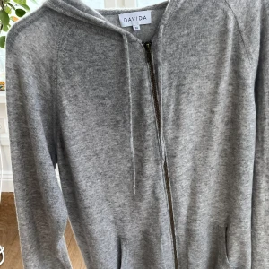 Kaschmir hoodie  - Säljer en stilren grå hoodie från Davida i mjukt material. Tröjan är använd i fåtal gånger, vilket gör att den är nästintill nyskick. Nypris ungefär 2,6| Mitt pris bara 1,2| Pris kan diskuteras vid snabb affär| Har ni några andra frågor är de bara att ställa de.