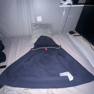 Mörkblå hoodie från Nike - Säljer en mörkblå hoodie från Nike med dragkedja och huva. Tröjan har två fickor med svarta detaljer och en liten Nike-logga på bröstet. Perfekt för en avslappnad stil.