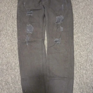 Svarta jeans med slitningar från Xthree - Snygga svarta jeans från Xthree med coola slitningar på framsidan. De har en klassisk femficksdesign och knäppning med knapp och dragkedja. Perfekta för en avslappnad stil.