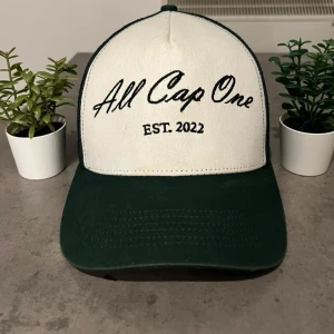 All Cap One keps - Snygg vit och grön keps från All Cap One. Den är helt slutsåld och går just nu inte att få tag i från deras hemsida. Storleken är justerbar så du kan hitta din rätta passform. Hör av dig vid minsta fundering.🙏😊