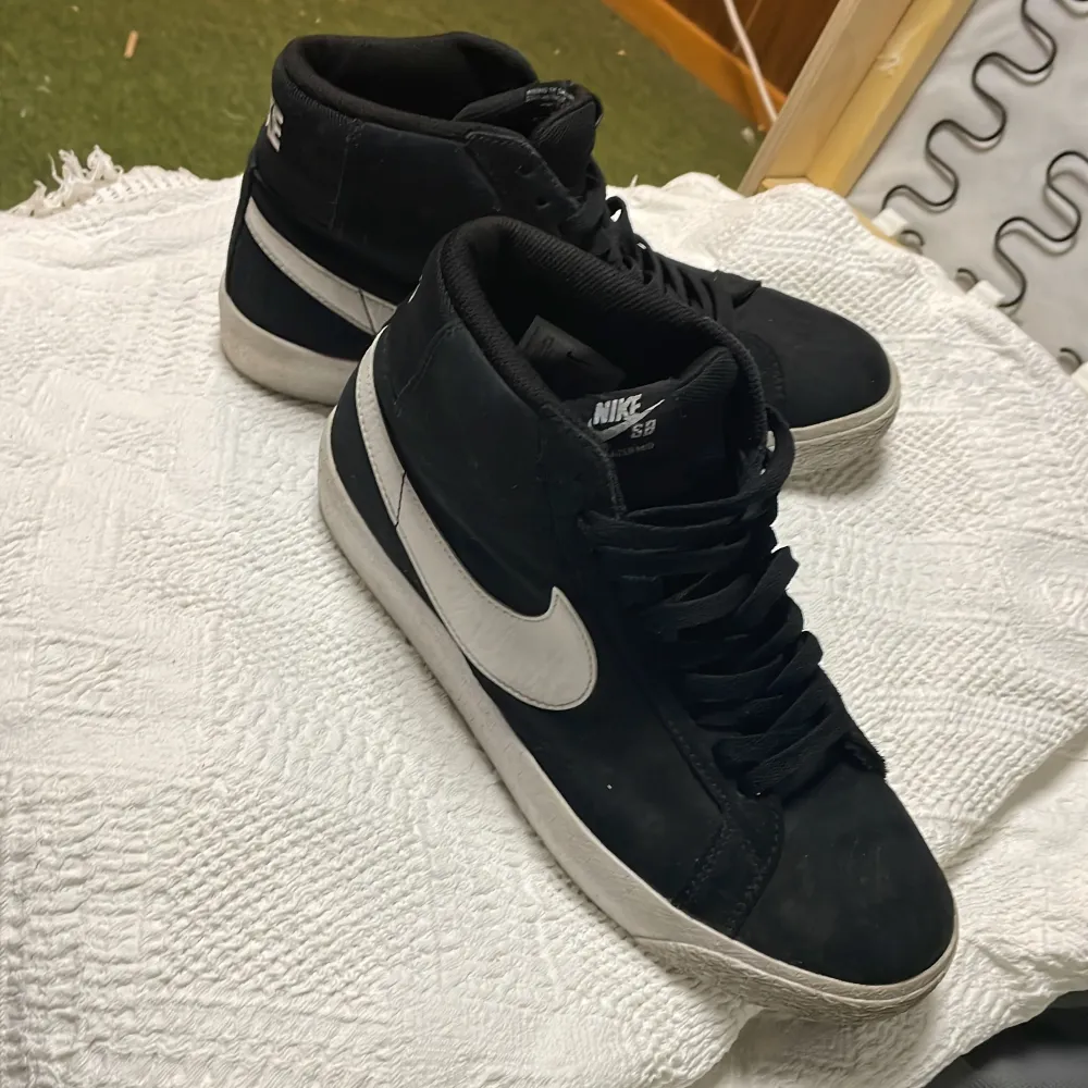 Säljer ett par svarta Nike sneakers i bra skick. De har en vit sula och den klassiska vita swoosh-loggan på sidan. Skorna har snörning och är perfekta för vardagsbruk. Passar både till jeans och träningskläder. Skorna är endast avtorkade men blir nästan som nya med en ordentlig rengöring. . Skor.