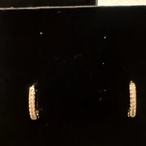 Guldörhängen med glittriga detaljer - Två par Säljer ett par eleganta guldörhängen med glittriga detaljer. De är små och perfekta för både vardag och fest. Örhängena har en klassisk design som passar till alla outfits. Perfekt present eller tillägg till din egen smyckessamling!