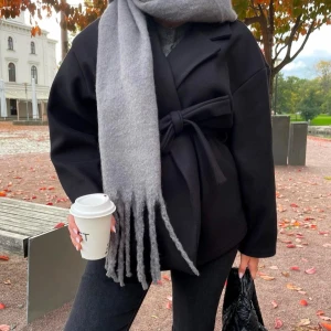 Svart kappa med knytband - Säljer en stilren svart kappa med knytband i midjan. Perfekt för höst och vinter för att hålla sig varm och snygg under kyliga dagar. 🖤Det är djurhår på den men kommer ta bort det så gott det går innan jag fraktar. Köptes för 400, kan diskutera priset🤍