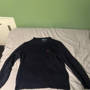 Mörkblå stickad tröja från Ralph Lauren L - Säljer en snygg mörkblå stickad tröja från Ralph Lauren med deras ikoniska röda logga på bröstet. Tröjan har långa ärmar och ribbade kanter som ger en klassisk look. Perfekt för både höst och vinter, och passar till alla tillfällen. Skön och stilren!   Skick: 9/10 Storlek: L