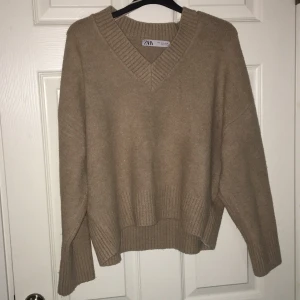 Beige stickad tröja från Zara - Mysig beige stickad tröja från Zara i storlek S. Den har en v-ringad hals och långa ärmar med ribbade detaljer vid ärmslut och nederkant. Perfekt för kyliga höst- och vinterdagar. Superfin att matcha med jeans eller kjol! Mycke bra skick! 
