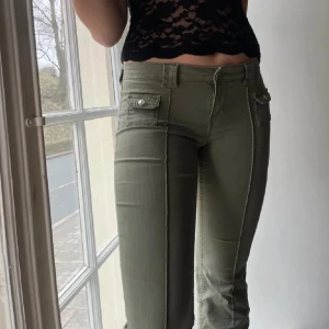 Assnygga jeans! - Säljer ett par olivgröna cargopants i mycket bra skick. De har en tight passform och är lågmidjade med snygga fickdetaljer på sidorna. Perfekta för en avslappnad och stilren look. Passar bra till både vardag och fest! Strl m men passar s lika bra! Förra ägarens bilder!