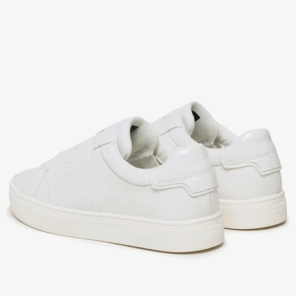 Snygga vita sneakers från Calvin Klein i skinn. De har en stilren design med elastiska band över foten istället för traditionell snörning. Perfekta för en casual look och passar till nästan allt i garderoben. Sulan är vit och har ett diskret mönster för bra grepp. Perfekta för vår och sommar!. Skor.