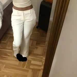 Vita  kostymbyxor från BikBok - Säljer ett par snygga vita byxor från BikBok i storlek 34. Modellen är i flare med en snygg slit på sidan av byxorna. Byxorna är lite genomskinliga, har använt dom endast 1 gång men är som nya!!!!😍