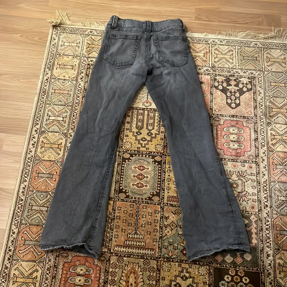 Säljer ett par grå bootcut jeans från Gina Tricot i storlek 158. De har en klassisk femficksdesign och stängs med dragkedja och knapp. Perfekta för en avslappnad stil och passar bra till både vardag och fest. Skicket är bra och de är bekväma att bära.. Jeans & Byxor.