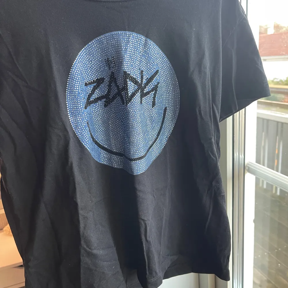 Säljer en svart t-shirt från Zadig & Voltaire med ett smiley-tryck. Superfin men kommer inte till användning. Tröjan har tappat några av stenarna men det är inget som syns🩷Skriv vid frågor. T-paidat.