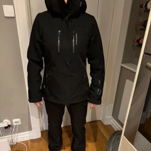 Svart skidjacka  - Säljer denna soft shell skidjacka i strl 36 som är använd på två skidsemester. Jackan är från Swedemount. Det finns Snölås, Liftkortshållare och luvan går att få över hjälmen om man vill. 😍🙏🏽
