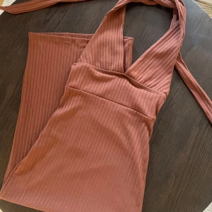 Brun ribbad klänning - Snygg brun ribbad klänning med djup v-ringning och ärmlös design. Perfekt för en kväll ute eller en fest. 