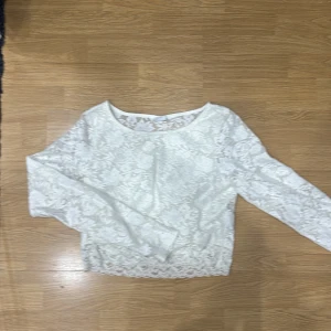 Vit spetsblus - Säljer en superfin vit spetsblus med långärmad design. Perfekt för både vardag och festliga tillfällen. Blusen har en elegant och feminin stil med ett vackert spetsmönster som ger en romantisk touch. Passar perfekt till jeans eller kjol för en chic look.