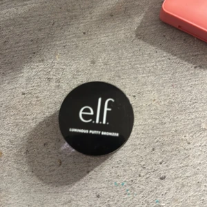 Luminous Putty Bronzer från e.l.f. - Säljer en Luminous Putty Bronzer från e.l.f. i en snygg gyllene nyans. Perfekt för att ge ansiktet en solkysst look med en naturlig lyster. Kommer i en praktisk liten burk som är lätt att ta med sig. Perfekt för både vardag och fest!