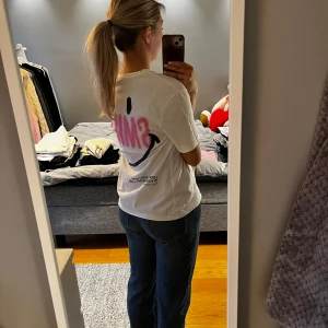 Vit t-shirt med Smiley från Zara - Säljer en superfin vit t-shirt från Zara med ett stort rosa och svart Smiley-tryck på baksidan. Perfekt passform. Använd ca 2 gånger. 