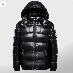 Svart pufferjacka med huva - Säljer en snygg svart pufferjacka i glansigt material. Jackan har en praktisk huva och dragkedja framtill. Perfekt för kalla vinterdagar! 🖤jackan är helt oanvänd, prislapp finns på. Säljer den pga den passade inte mig.