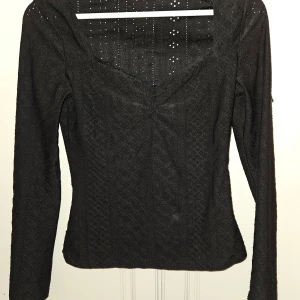 Svart topp - Använd 1 ggr Svart topp med långa ärmar och spetsdetaljer. Toppen har en rund halsringning och en figursydd passform. Se sista bild för mönstret