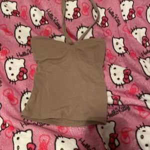 Beige tubtopp från Gina Tricot - Säljer en snygg beige tubtopp från Gina Tricot i storlek XS. Toppen är ribbad och har en knytning i halsen för extra stil. Perfekt för sommardagar eller en utekväll. Den är i mycket bra skick och redo för nya äventyr!