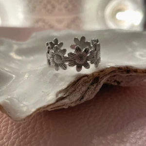 Silverfärgad ring med blommor - Superfin silverfärgad ring med ett mönster av små blommor runt om. Perfekt för att ge en söt och stilren touch till din outfit. Ringen är justerbar och passar de flesta storlekar. Perfekt för både vardag och fest! 🌸helt ny också!