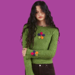 Grön stickad tröja med blommor - Superfin grön stickad tröja med färgglada blommor på bröstet och ärmen. Perfekt för att liva upp garderoben! Den är långärmad och har en mysig passform. Passar perfekt till höst och vår. Från Unif.