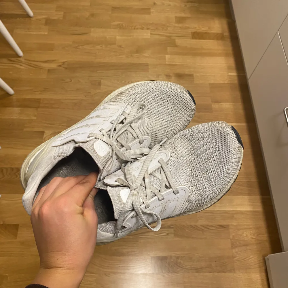 Säljer ett par vita Adidas Ultraboost i bra skick. De har en stickad ovandel som ger en skön passform och Boost-sula för extra komfort. Perfekta för både träning och vardag. Snörning framtill och klassiska tre ränder på sidan.. Skor.