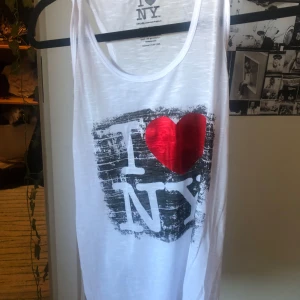 Vit linne med I Love NY-tryck - Säljer ett vitt linne från IDEA i storlek L men sitter ganska tajt. Materialet är lätt och bekvämt. Linnet har inte använt och är väldigt nytt. 