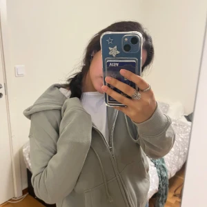 Grön huvtröja från H&M Divided - Säljer en mysig grön huvtröja från H&M Divided i storlek XXS. Tröjan har en dragkedja framtill och en skön huva. Perfekt för vardagsbruk eller en chill dag hemma. Den är i bra skick och superbekväm att ha på sig. Passar perfekt till jeans eller leggings!