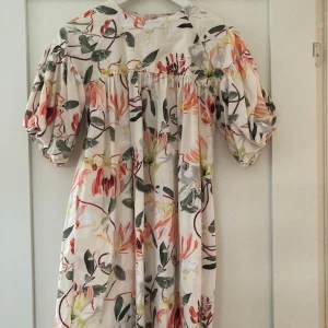 Blommig klänning från Molo - Superfin blommig klänning från Molo i storlek 146/152. Den har puffiga kortärmar och ett härligt färgglatt mönster med blommor i olika nyanser. Perfekt för sommarens alla fester eller bara en solig dag ute. Klänningen är i mycket bra skick och redo för nya äventyr! 🌸