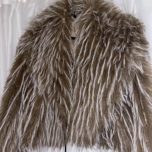 Brun pälsjacka - Säljer en superfluffig brun pälsjacka som är perfekt för att hålla sig varm och snygg under kyliga dagar. Jackan har en lyxig känsla med långa ärmar och en härlig volym. Den är i mycket bra skick och passar perfekt för höst och vinter. Passar XS/S/M