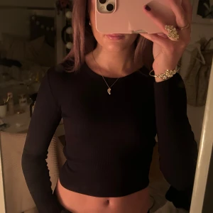Svart ribbad croppad topp - Säljer en snygg svart ribbad croppad topp med långa ärmar. Perfekt för en kväll ute eller en avslappnad dag. Toppen är i bra skick och passar till det mesta i garderoben. I barnstorlek men passar xs-s