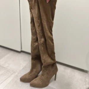 Bruna mockastövlar med klack - Snygga bruna stövlar i mocka med hög klack och spetsig tå. Perfekta för höst och vinter, och funkar lika bra till vardags som till fest. Stövlarna är oanvända. Storlek 37. Pris 300kr