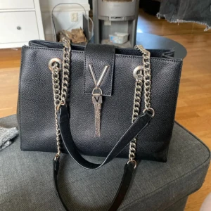 Mario Valentino väska - Valentino väska i modellen ”divina” och färgen ”nero”, det finns synliga defekter på den och den är lite smutsig inuti, men vid intresse så kan jag försöka få rent det lilla. Skinnimitation. Nypris 1295 kr. Jag säljer väskan då jag inte längre har användning av den🥰