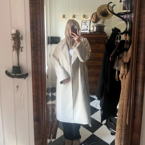 Beige kappa  - Säljer en superfin beige kappa i ull med bälte i midjan. Perfekt för höst och vår! Den har en klassisk och stilren design med långa ärmar och en rak passform. Kappan är i mycket bra skick och passar både till vardags och fest. Storlek dam M.