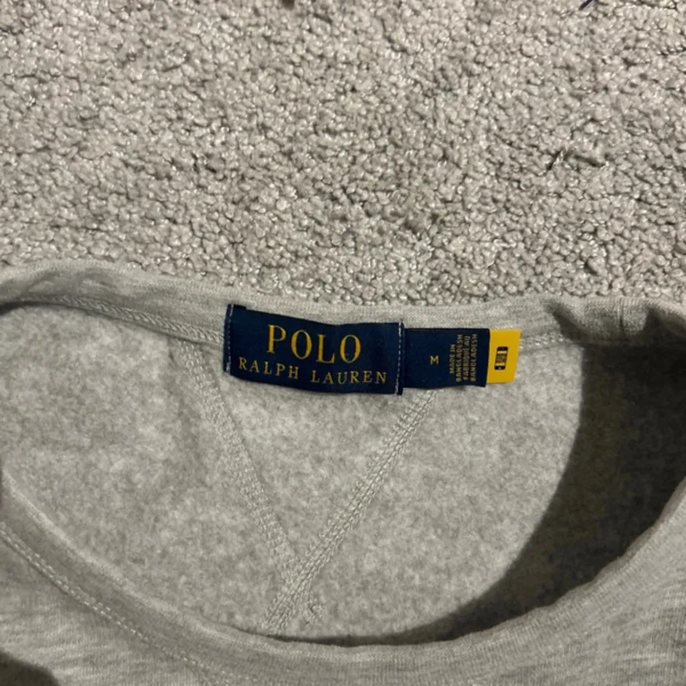 Säljer en stilren grå tröja från Polo Ralph Lauren i nyskick, endast användt ett par gånger. Den har en klassisk design med rund hals och det ikoniska logotypbroderiet på bröstet. Perfekt för både vardag och lite finare tillfällen.. Tröjor & Koftor.