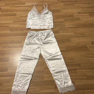 Vit satin pyjamas med spetsdetaljer - Säljer en superfin vit pyjamas i satin med spetsdetaljer. Helt ny säljer endast pga fel storlek. Nypris 299.