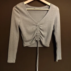 Grå ribbad topp från SHEIN - Säljer en snygg grå ribbad topp från SHEIN i storlek S. Den har en v-ringad design med snörning framtill som ger en cool look. Perfekt för både vardag och fest! 💫