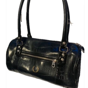 Äkta vintage handväska  - Svart lack-skinn imitation handväska Rymmer mycket och är bekväm att ha på axeln  Köpt från second hand butik  Bra skick generellt inga större defekter förrutom handtagens tyg som blivit slitna gått sönder och ihoplimmade, men bara yttre skador 