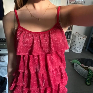 Söt volangtopp - En söt röd volangtopp med lite guldigt glitter i.  Säljer dåliga tröttnat