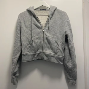 Grå zip hoodie - Säljer denna super söta och mjuka korta zip hoodie från brandy Melville 
