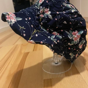 Blommig hatt från Seeberger - Säljer en superfin blommig hatt från Seeberger. Den är mörkblå med ett vackert blommönster i rosa och grönt. Perfekt för vår och sommar! Hatten är i one size och passar de flesta. Den är i nyskick och redo för nya äventyr!