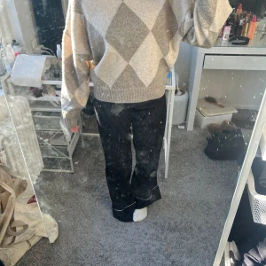 Beige och grå tröja från Pringle of Scotland x H&M - Säljer en superfin beige och grå tröja från Pringle of Scotland x H&M. Den har ett snyggt rutigt mönster och är perfekt för höst och vinter. Tröjan är stickad och har långa ärmar med ribbade muddar. Den är både stilren och bekväm, perfekt för att hålla sig varm och trendig!