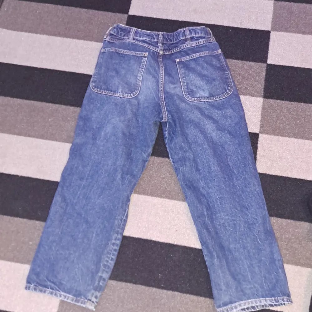 Säljer ett par blå baggy jeans i klassisk stil. De har en lös passform och är perfekta för en avslappnad look. Jeansen har fickor både fram och bak, och stängs med en dragkedja och knapp. Perfekta för vardagsbruk!. Jeans & Byxor.