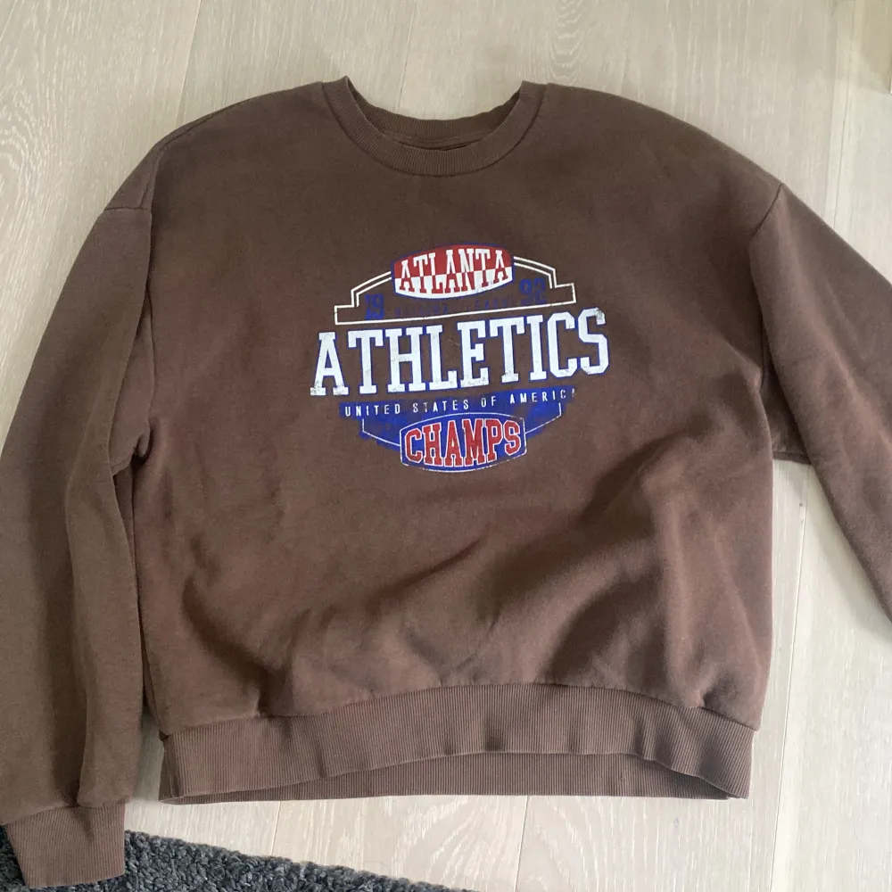 Brun, atheltics crewneck från Gina tricot. Original pris= 400kr, finns inte längre. Storlek M. Topp condition, jätte mjuk och håller dig varm. Oversized.. Hoodies.