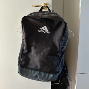 Ryggsäck Adidas - Använt ryggsäck många gånger till skolan. Alla dragkedjor är som nya. Den är ren och fin, inga repor förutom små på botten från att den stått på mark. Ganska rymlig, bara ett fack inuti utan dragkedja. 