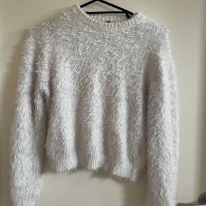 Vit fluffig tröja - Säljer en supermysig vit fluffig tröja som är perfekt för kyliga dagar. Den har en normal passform och långa ärmar, vilket gör den idealisk för både höst och vinter.