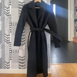 Svart lång kappa  - Svart lång kappa med två rymliga fickor och ett band runt midjan😍 kappan är sparsamt använd o passar perfekt till höst o vinter❤️