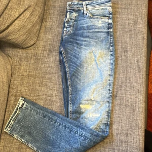 Blåa jeans från Jack & Jones - Såljer dessa blåa jeans från Jack & Jones med slitningar/ Modell -Slim/Glenn / skicket är super / Storlek 29/34 / Vid funderingar är det bara att höra av sig!🙌