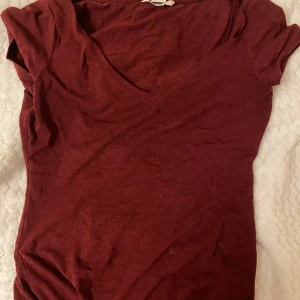 Vinröd topp från Banana Republic - Säljer en snygg vinröd topp från Banana Republic. Den är i storlek XS och har en v-ringad design med korta ärmar. Perfekt för både vardag och fest!