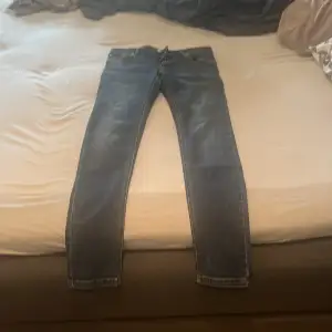 Säljer ett par klassiska blå jeans från Wrangler. De har en snygg straight passform och är i bra skick. Jeansen har fem fickor och stängs med dragkedja och knapp. Perfekta för både vardag och fest!